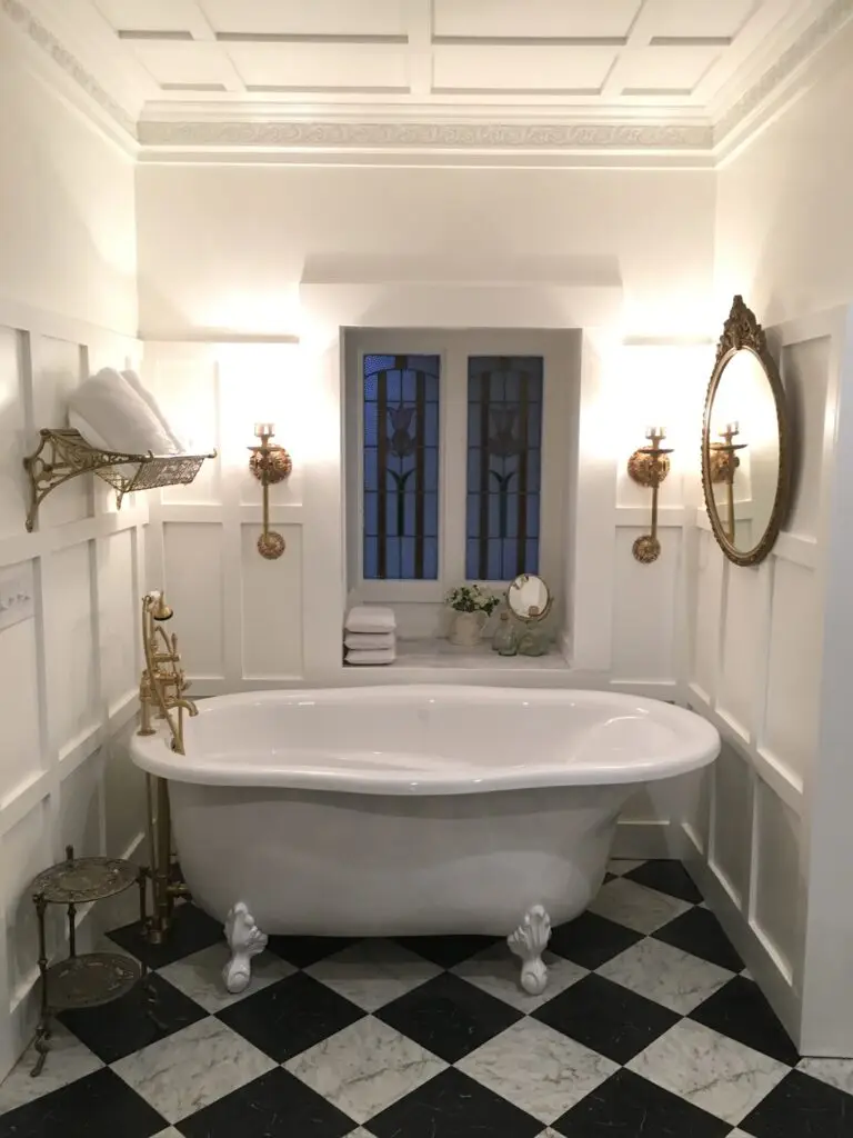 “Primary bathroom with freestanding soaking tub, brass fixtures, wall sconces, and patterned tile floor for a retreat-style feel.”