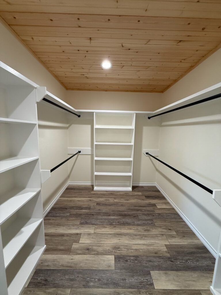 “Spacious walk-in closet with built-ins, hanging rods, open shelving, and luxury vinyl plank flooring for organized storage.”