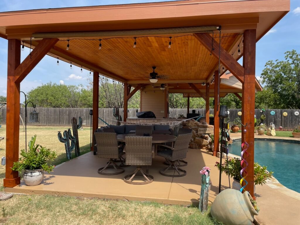 “Outdoor kitchen and covered patio with seating, string lights, and open-air living space designed for entertaining.”
